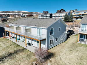 Back of property featuring a patio, roof with shingles, a yard, and a residential view