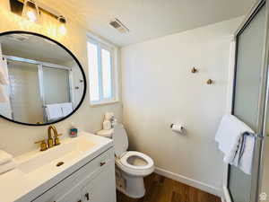 Full bath featuring a textured ceiling, dark wood-style floors, vanity, and a stall shower