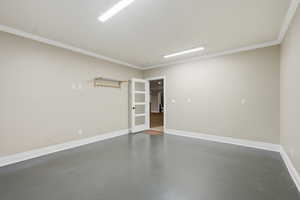 Unfurnished room featuring finished concrete flooring and ornamental molding