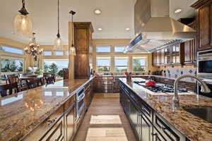 Kitchen with island exhaust hood, recessed lighting, tasteful backsplash, stone counters, and decorative light fixtures