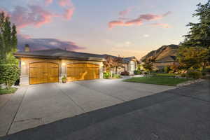 View of front of house featuring an attached garage, concrete driveway, a chimney, and stucco siding