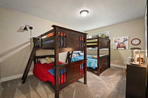 Carpeted bedroom featuring a textured ceiling and baseboards