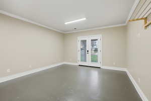 Spare room featuring french doors, concrete flooring, and crown molding