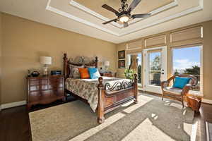 Bedroom with hardwood / wood-style flooring, access to outside, a raised ceiling, ceiling fan, and crown molding