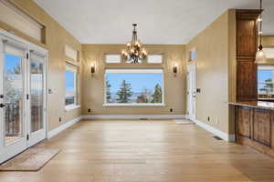 Unfurnished dining area with light wood-style flooring, a chandelier, and healthy amount of natural light