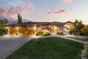 View of front facade with an attached garage, a yard, concrete driveway, and stucco siding
