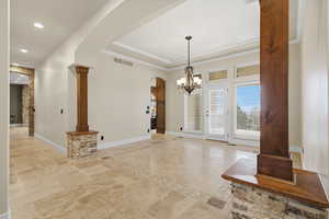 Unfurnished dining area featuring arched walkways, decorative columns, recessed lighting, a chandelier, and inlaid floor details