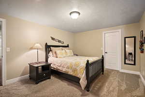 Carpeted bedroom featuring a textured ceiling and baseboards