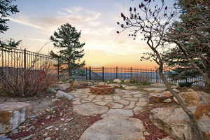 Patio terrace at dusk with an outdoor fire pit, a patio, and a fenced backyard