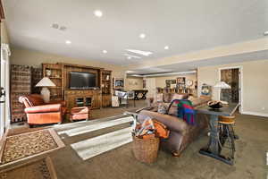 Living area with recessed lighting and dark colored carpet
