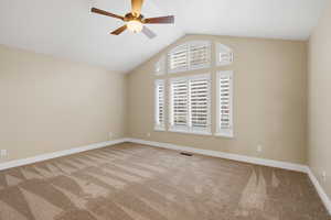 Empty room featuring ceiling fan, carpet, and lofted ceiling