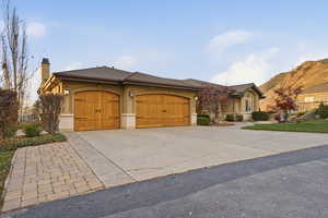 View of front of home with stucco siding, concrete driveway, an attached garage, and a chimney