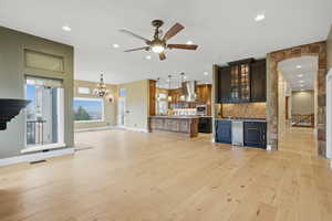 Unfurnished living room featuring light wood finished floors, a chandelier, recessed lighting, and ceiling fan