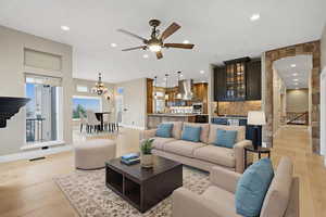 Living room with stairs, recessed lighting, light wood finished floors, a chandelier, and ceiling fan