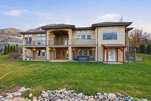 Rear view of house featuring a hot tub, stucco siding, a patio area, and a balcony