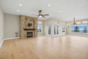 Unfurnished living room with recessed lighting, a fireplace, light wood-style floors, a chandelier, and a ceiling fan