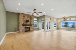 Unfurnished living room with recessed lighting, a fireplace, light wood finished floors, a chandelier, and ceiling fan