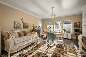 Bedroom with ornamental molding, a desk, multiple windows, wood finished floors, and a chandelier
