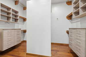 Walk in closet with dark wood-type flooring
