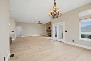 Unfurnished living room with recessed lighting, a fireplace, ceiling fan, a chandelier, and light wood-style floors