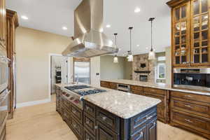 Kitchen featuring a center island, light stone countertops, island exhaust hood, light wood-type flooring, and pendant lighting