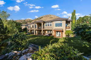 Back of house with a patio, stucco siding, a chimney, a lawn, and a mountain view