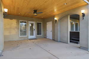 View of exterior entry featuring a ceiling fan, stucco siding, and a patio area