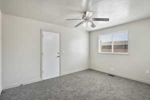 Carpeted primary room with a window, and ceiling fan