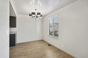Dining area with light wood-style flooring, a textured ceiling, and a chandelier