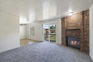 Living room featuring a brick fireplace, newer paint and carpet and sliding glass door to balcony.