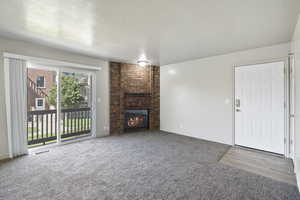 Living room featuring a brick fireplace, newer paint and carpet and sliding glass door to balcony.