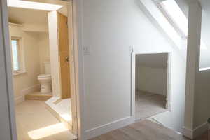 Bathroom with a skylight, a stall shower, and light tile patterned floors