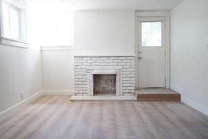 Unfurnished living room with wood finished floors and a brick fireplace