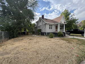 View of side of home with a porch, a chimney, brick siding, and roof with shingles