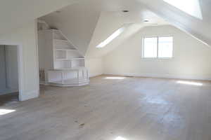 Bonus room featuring a skylight, lofted ceiling, and light wood finished floors