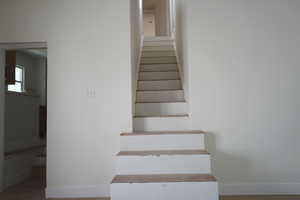 Stairs with wood finished floors and baseboards