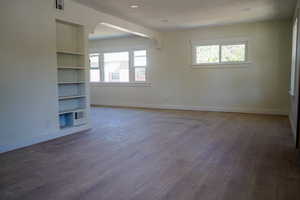 Spare room featuring dark wood finished floors, built in features, a textured ceiling, and arched walkways
