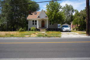 View of front facade with covered porch, a chimney, brick siding, and driveway