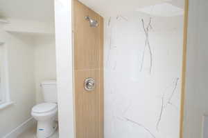 Bathroom with a marble finish shower and tile patterned flooring