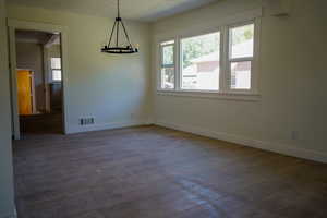 Unfurnished dining area with plenty of natural light, dark wood-style flooring, a chandelier, and a textured ceiling