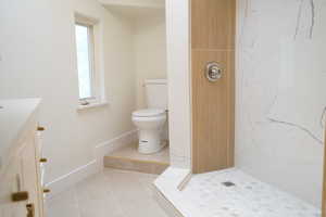 Full bathroom featuring a marble finish shower, light tile patterned flooring, and vanity