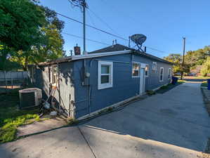 View of side of home featuring a chimney and a cooling unit