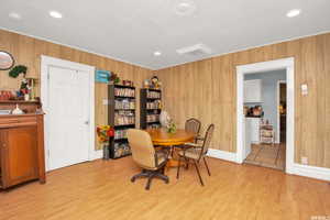 Dining area with light wood-style floors, wood walls, and recessed lighting