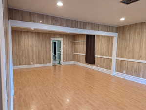 Unfurnished room with wood finished floors, recessed lighting, and wooden walls