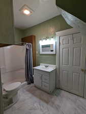 Bathroom with a textured wall, curtained shower, vanity, and marble look tiles