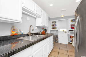 Kitchen featuring tile counters, freestanding refrigerator, white cabinets, light tile patterned floors, and white microwave