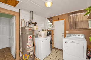 Washroom featuring water heater, washing machine and dryer, and light flooring