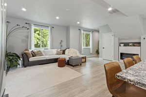 Living area with light wood-type flooring, a glass covered fireplace, and recessed lighting