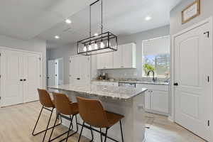 Kitchen featuring white cabinets, light wood-style flooring, a kitchen bar, and recessed lighting