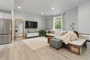 Living area with light wood-type flooring, recessed lighting, and arched walkways